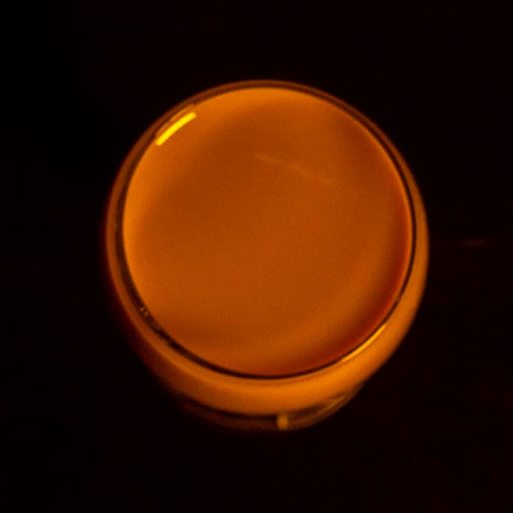 Taça de licor de doce de leite vista de cima, brilhando como um ponto de luz na penumbra